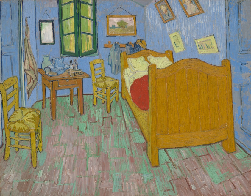 A bedroom with blue walls, a wooden bed, two chairs, and framed pictures.